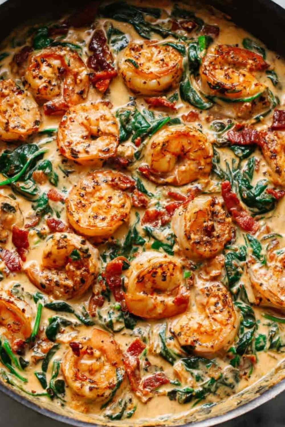 Tuscan shrimp in a creamy garlic sauce with spinach, artichokes, and sun-dried tomatoes in a large skillet